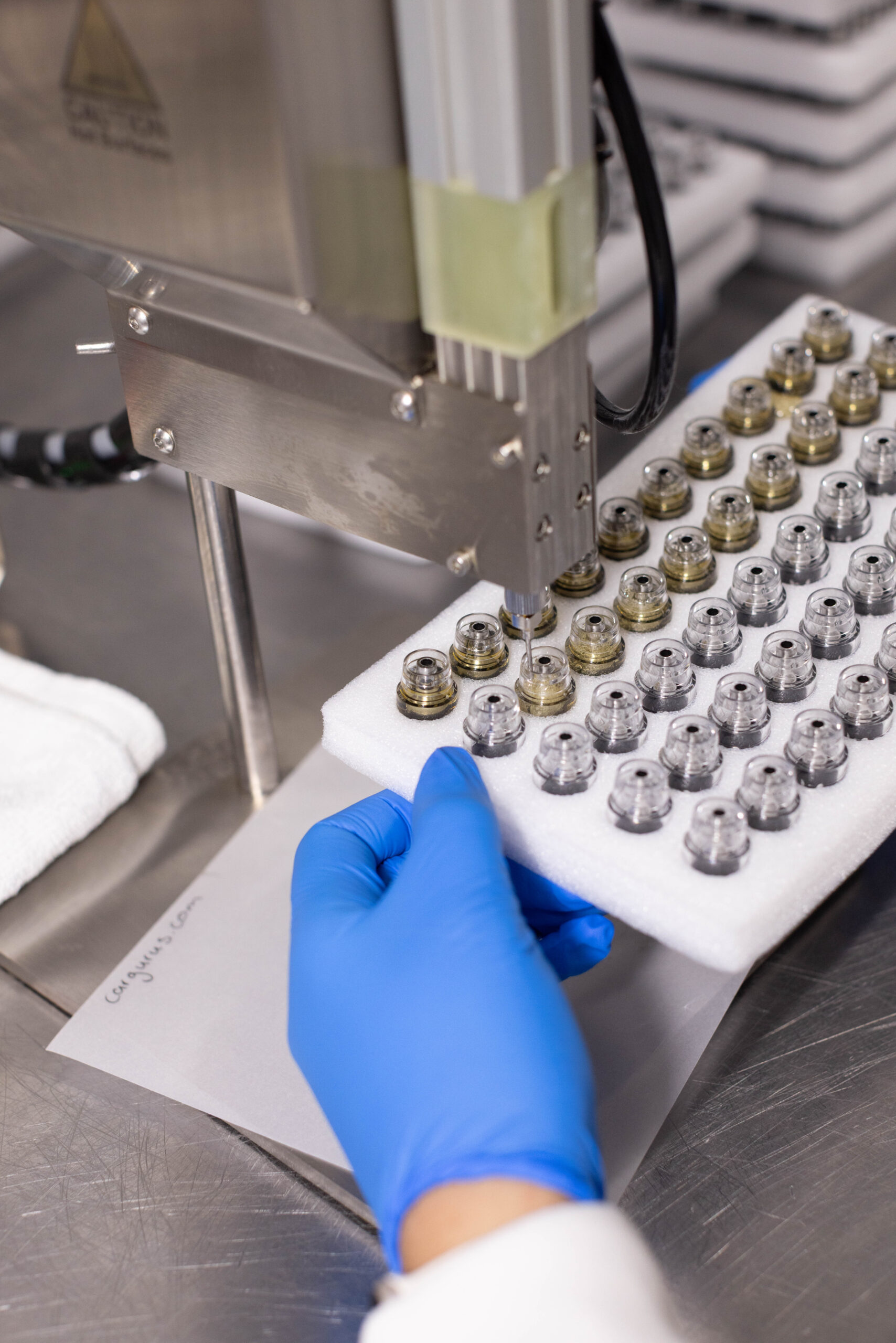 Vape cartridge hardware tray being positioned under filling machine